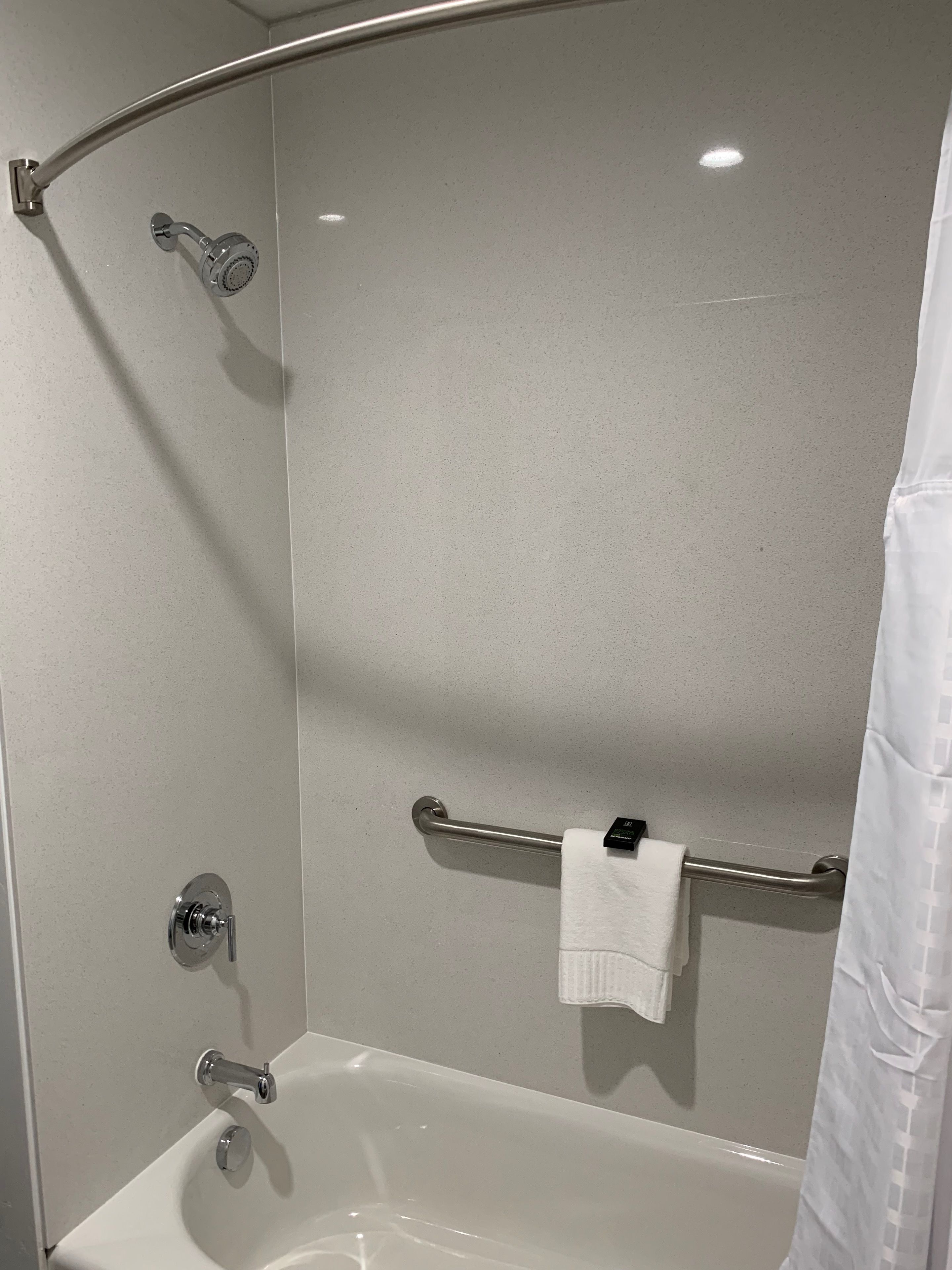 A modern bathroom with a bathtub, a shower, and a handrail.