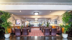 Un vestíbulo de hotel con una zona de estar central, un candelabro y plantas en macetas.