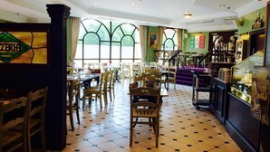 Un restaurante con suelo a cuadros, sillas y mesas de madera, y una escalera que sube a un nivel superior.