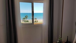 A room with a large window offering a view of the beach and ocean.
