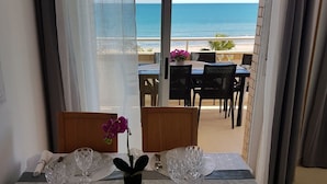 A dining area with a table set for four, overlooking a beach.