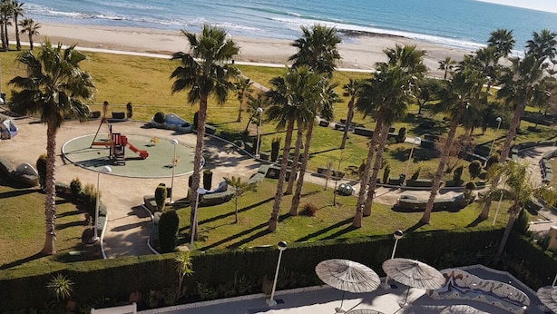 A swimming pool with a view of the beach and palm trees.
