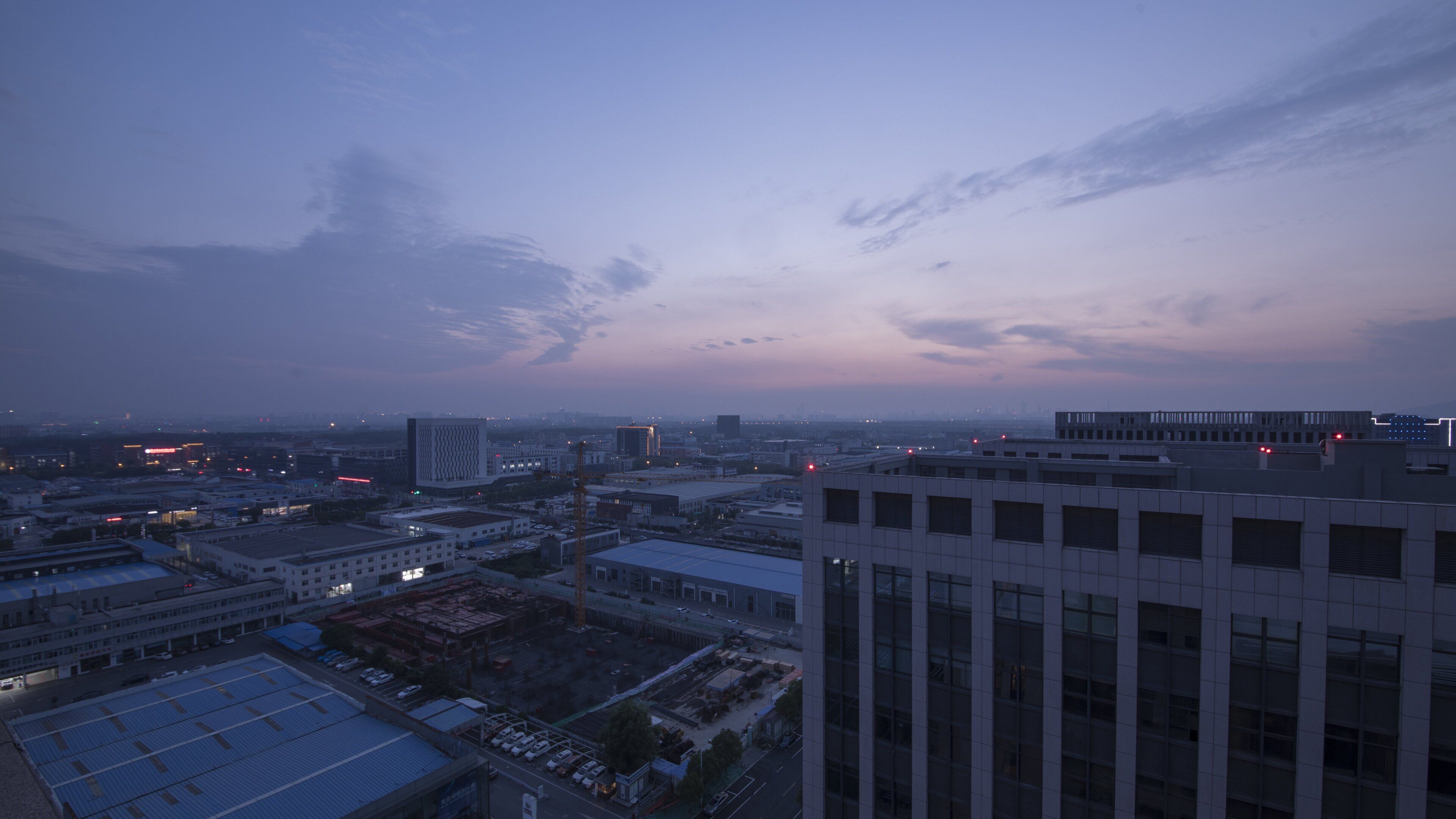 Une vue sur une ville au crépuscule, avec des bâtiments modernes et un ciel dégagé.