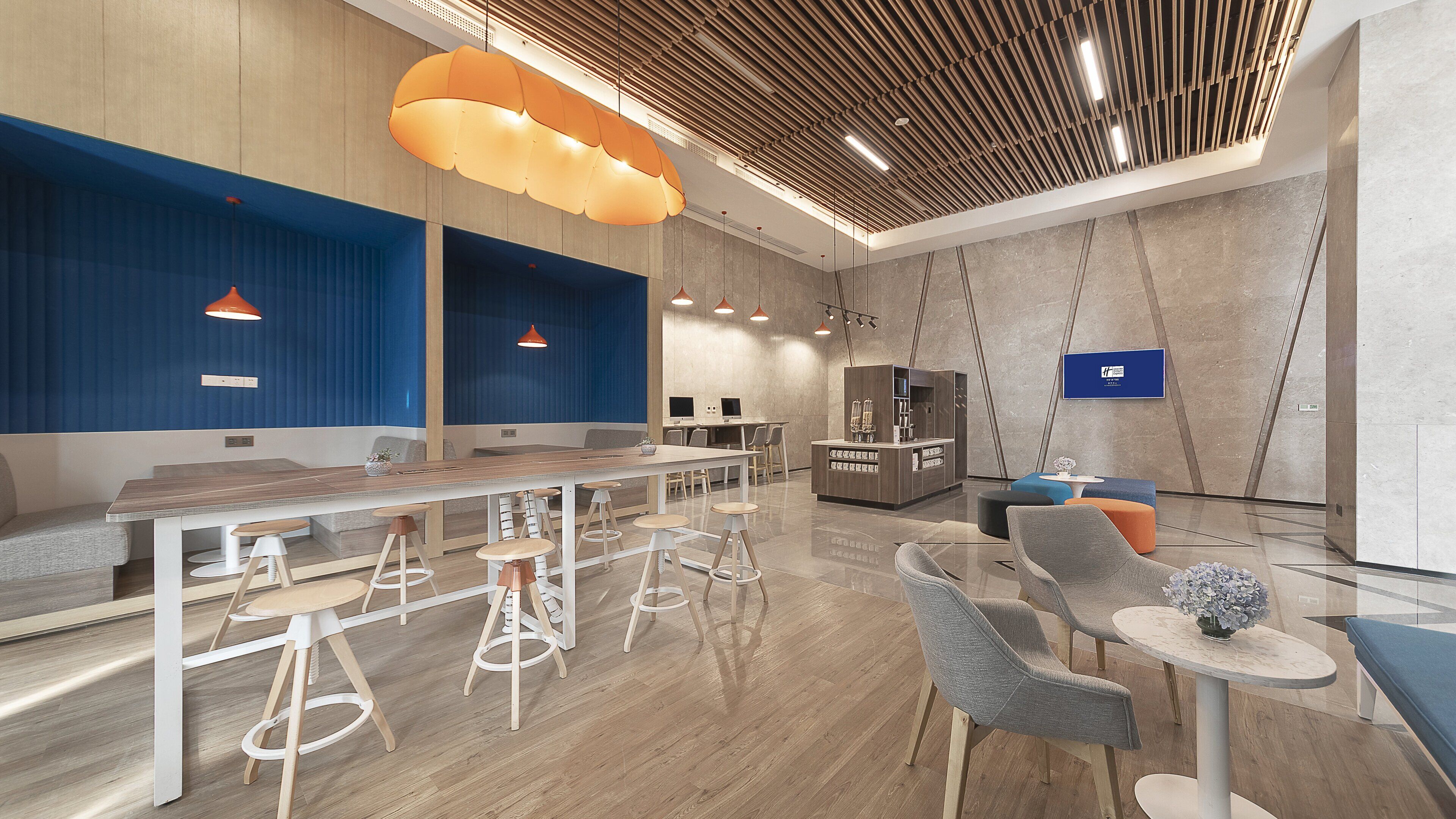 A modern interior with a long communal table, bar stools, and seating areas.