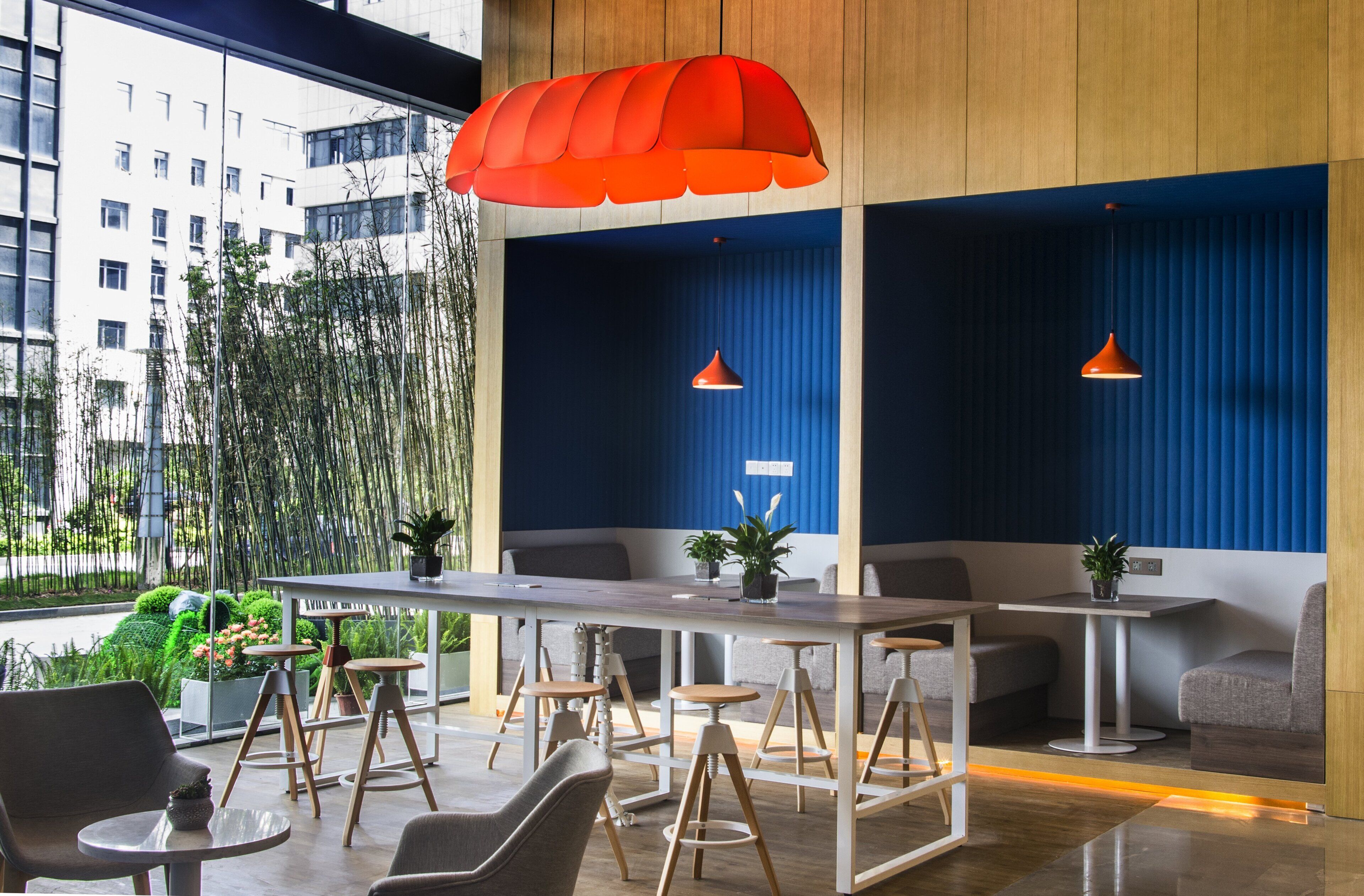 A modern bar area with a long table, multiple stools, and two pendant lights.