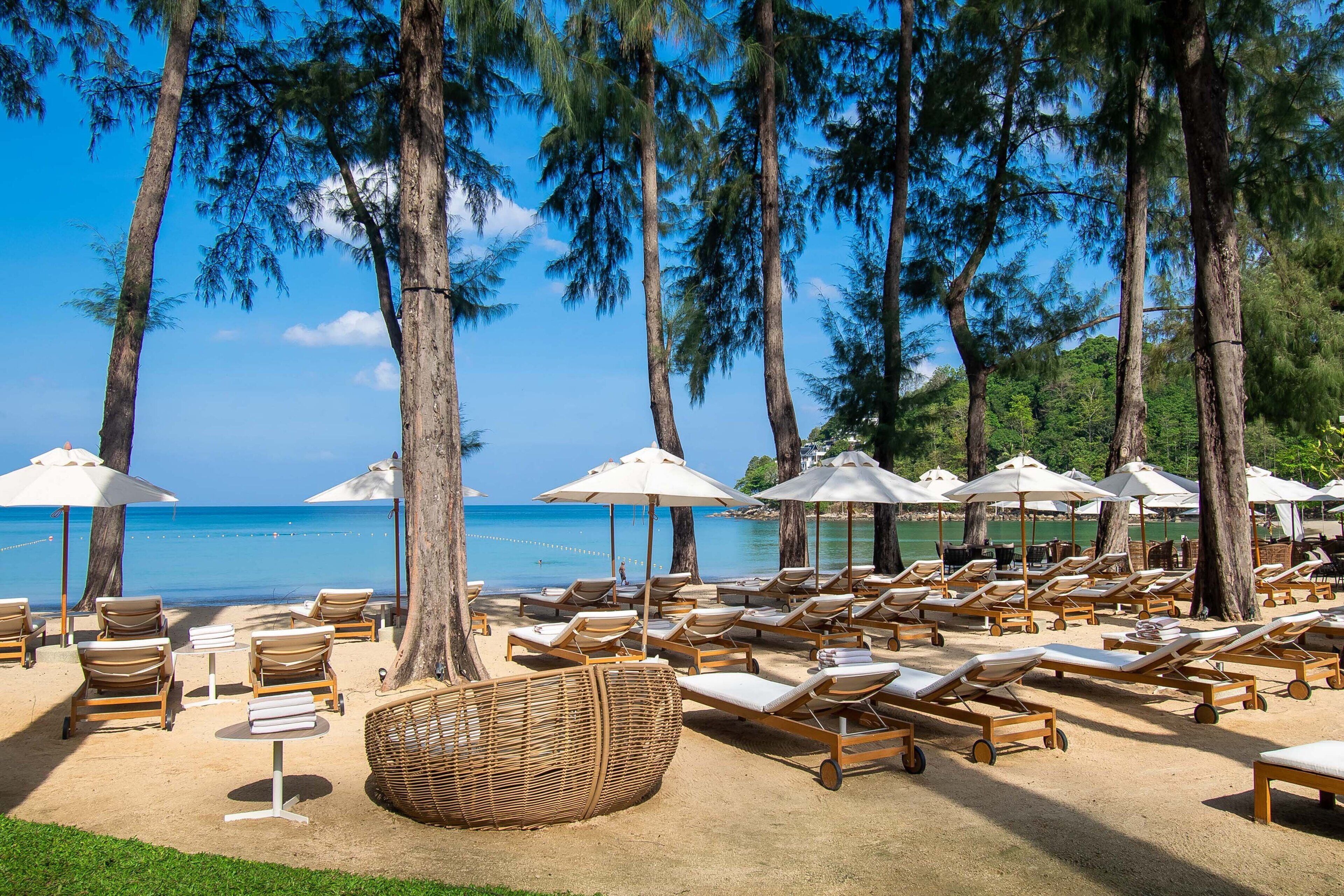 Um resort à beira-mar com espreguiçadeiras, guarda-sóis e vista para o oceano.