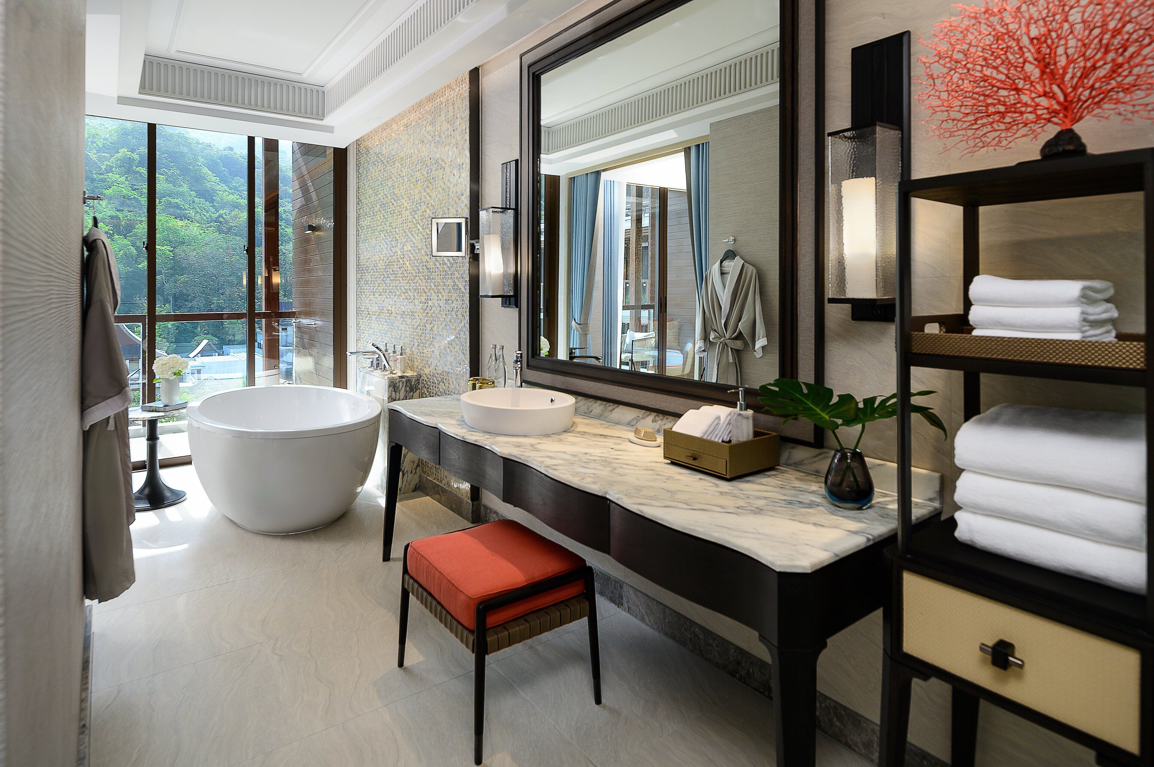 A modern bathroom with a large bathtub, a round sink, and a vanity with a mirror.