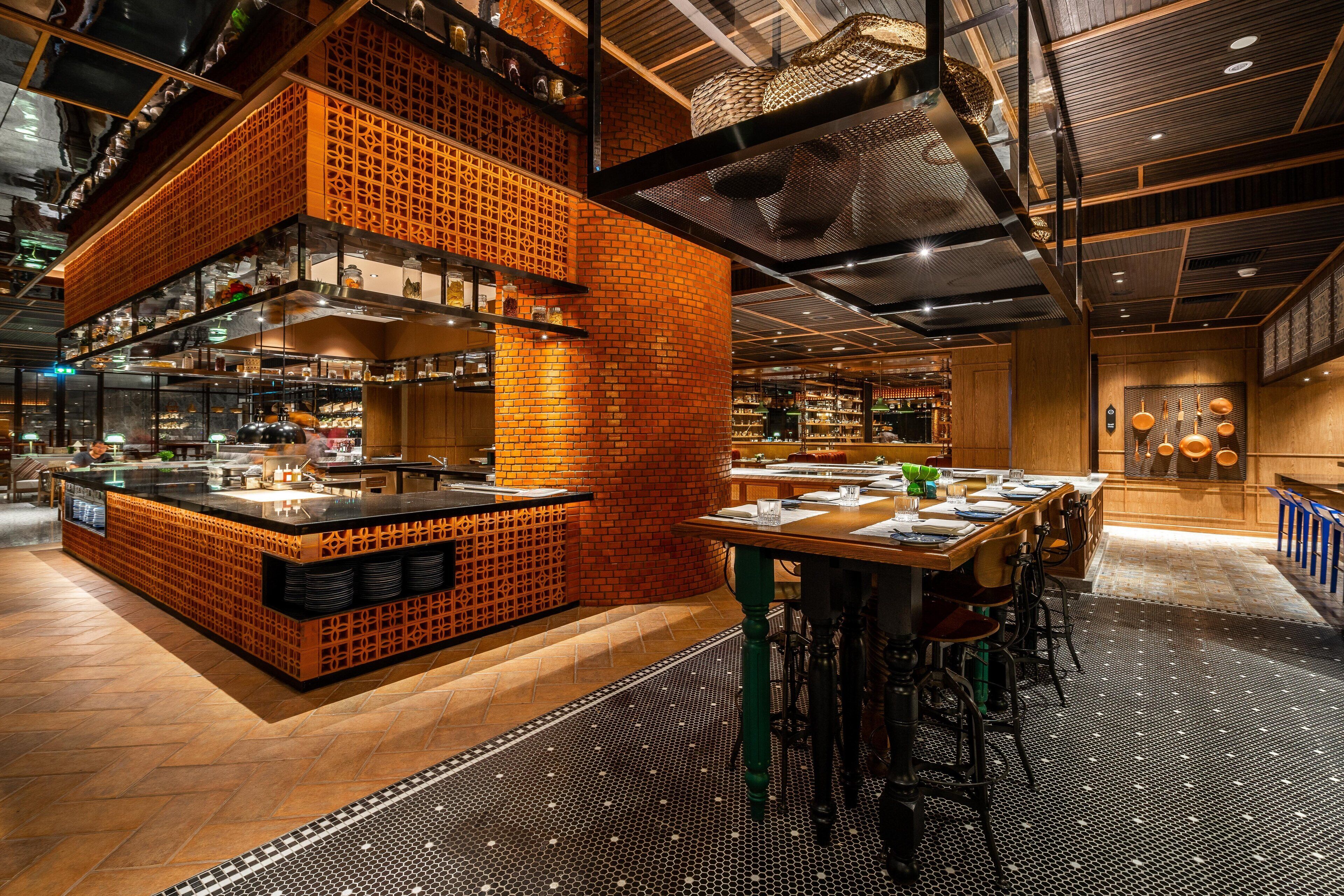 A modern restaurant interior with a brick accent wall, a central island, and a seating area with high stools.