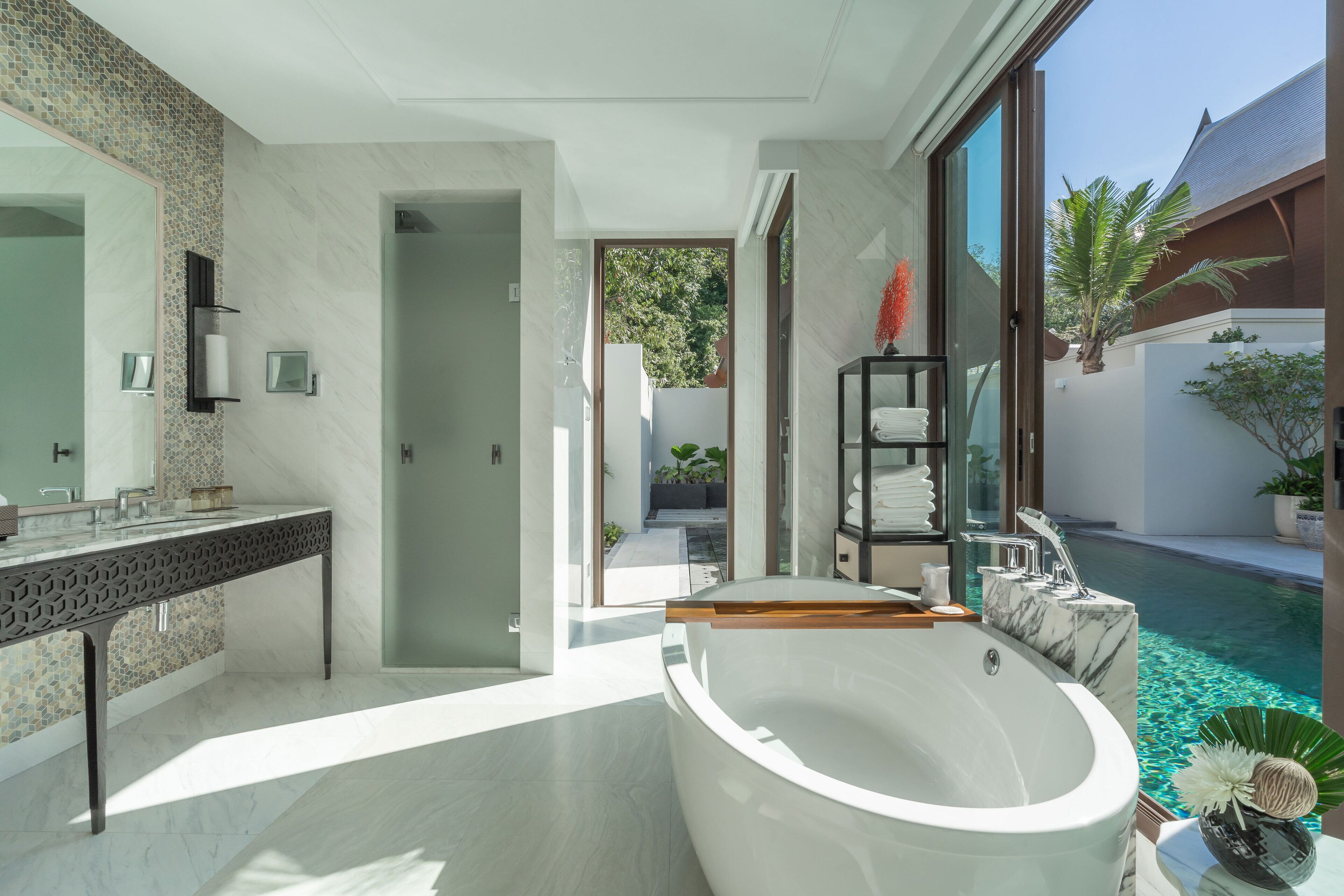 A modern bathroom with a large bathtub, a glass-enclosed shower, and a marble countertop.