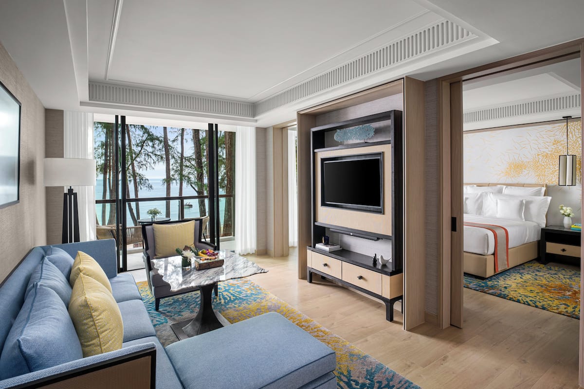 Een moderne hotelkamer met een grote televisie, een bank, een salontafel en een bed met nachtkastje.