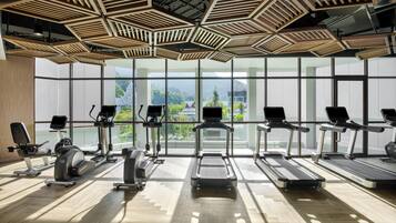A gym with exercise equipment, large windows, and a wooden ceiling design.
