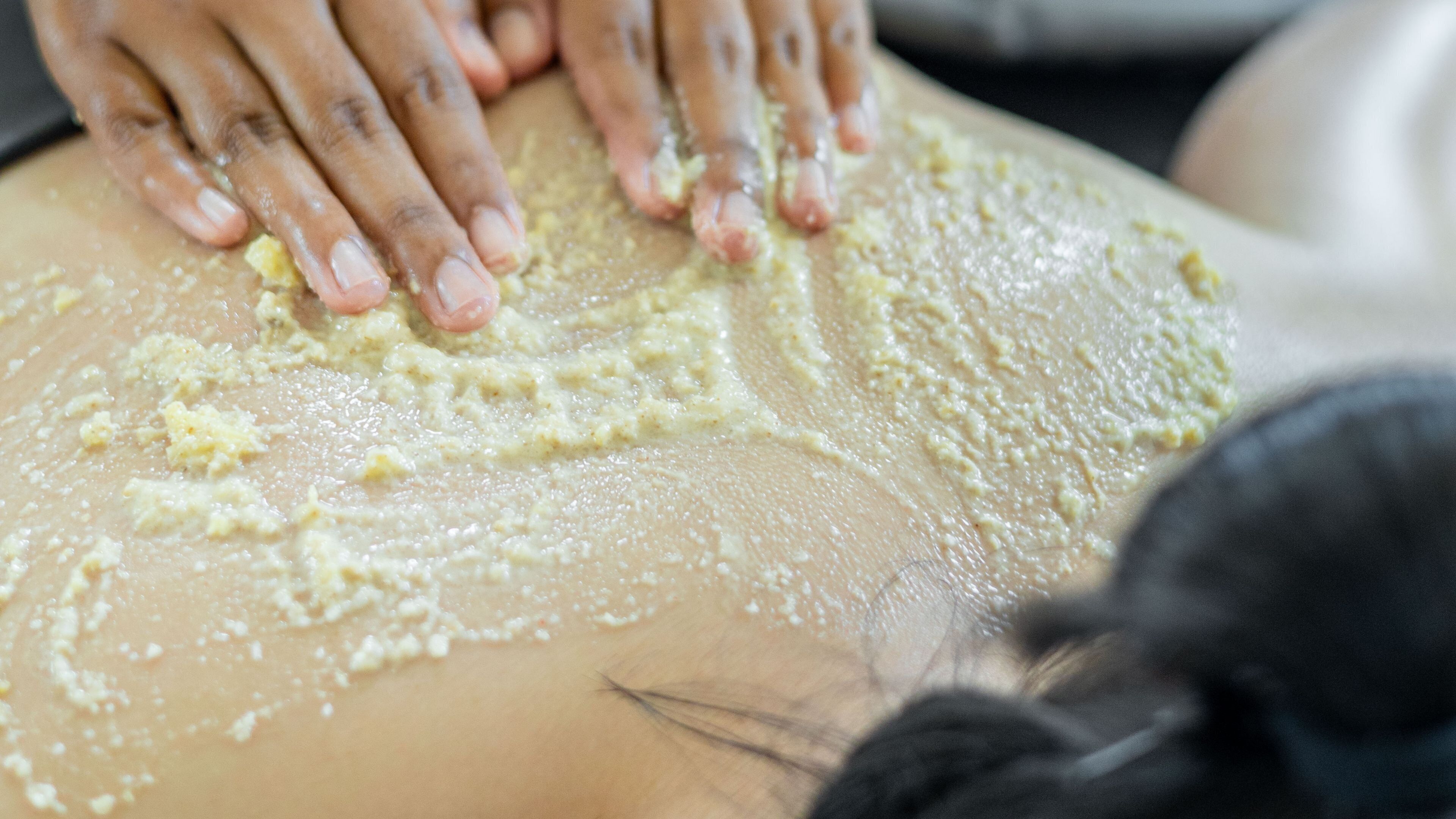 A close-up of hands applying a yellowish substance to a surface.
