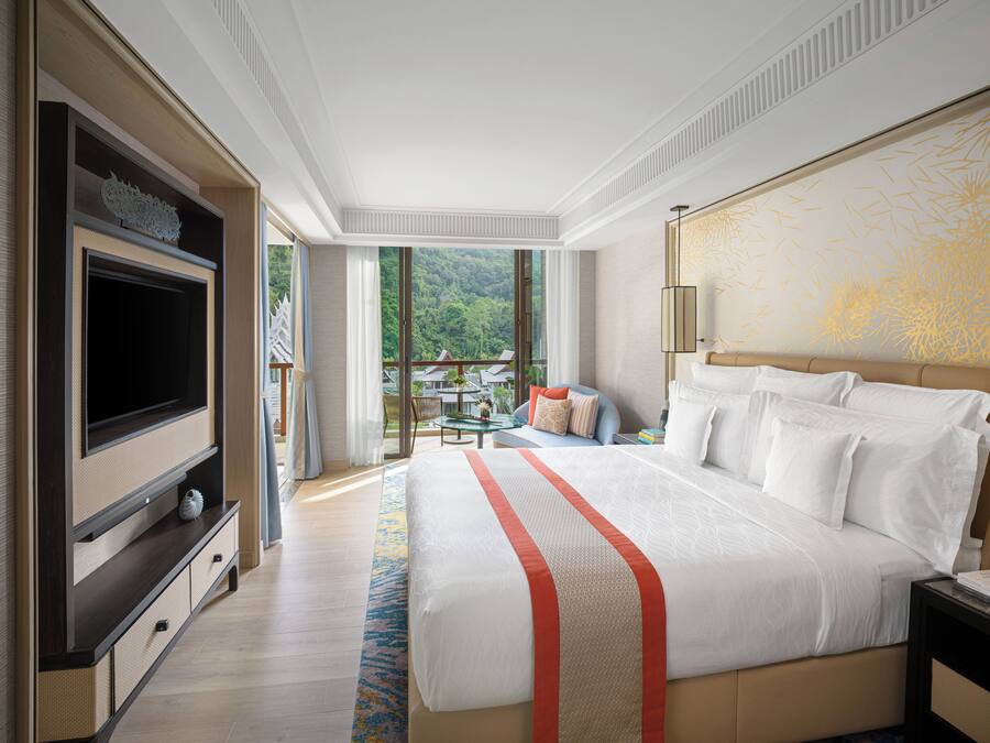Un dormitorio amplio con una cama grande, televisión y balcón con vistas al exterior.