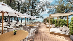A wooden deck with outdoor seating, including tables and chairs, and a canopy area with umbrellas.