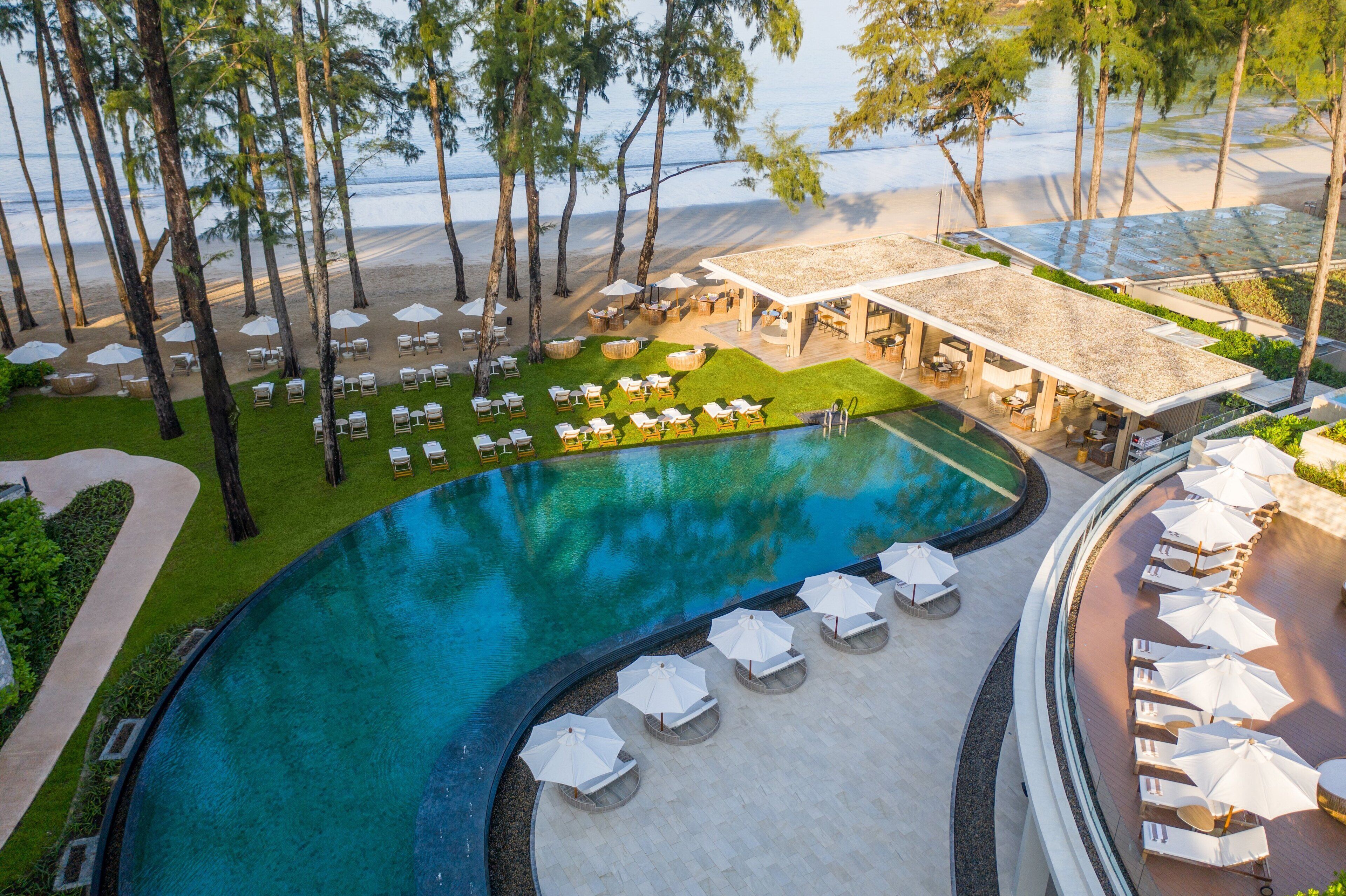 A resort with a swimming pool, lounge chairs, and a beach area.