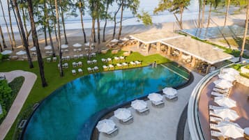 A resort with a swimming pool, lounge chairs, and a beach area.