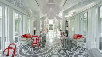 A spacious hallway with a patterned floor, white furniture, and large windows.