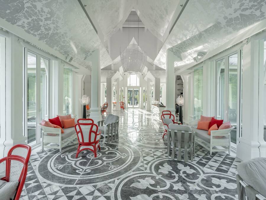 Un pasillo amplio con piso estampado, muebles blancos y ventanas grandes.