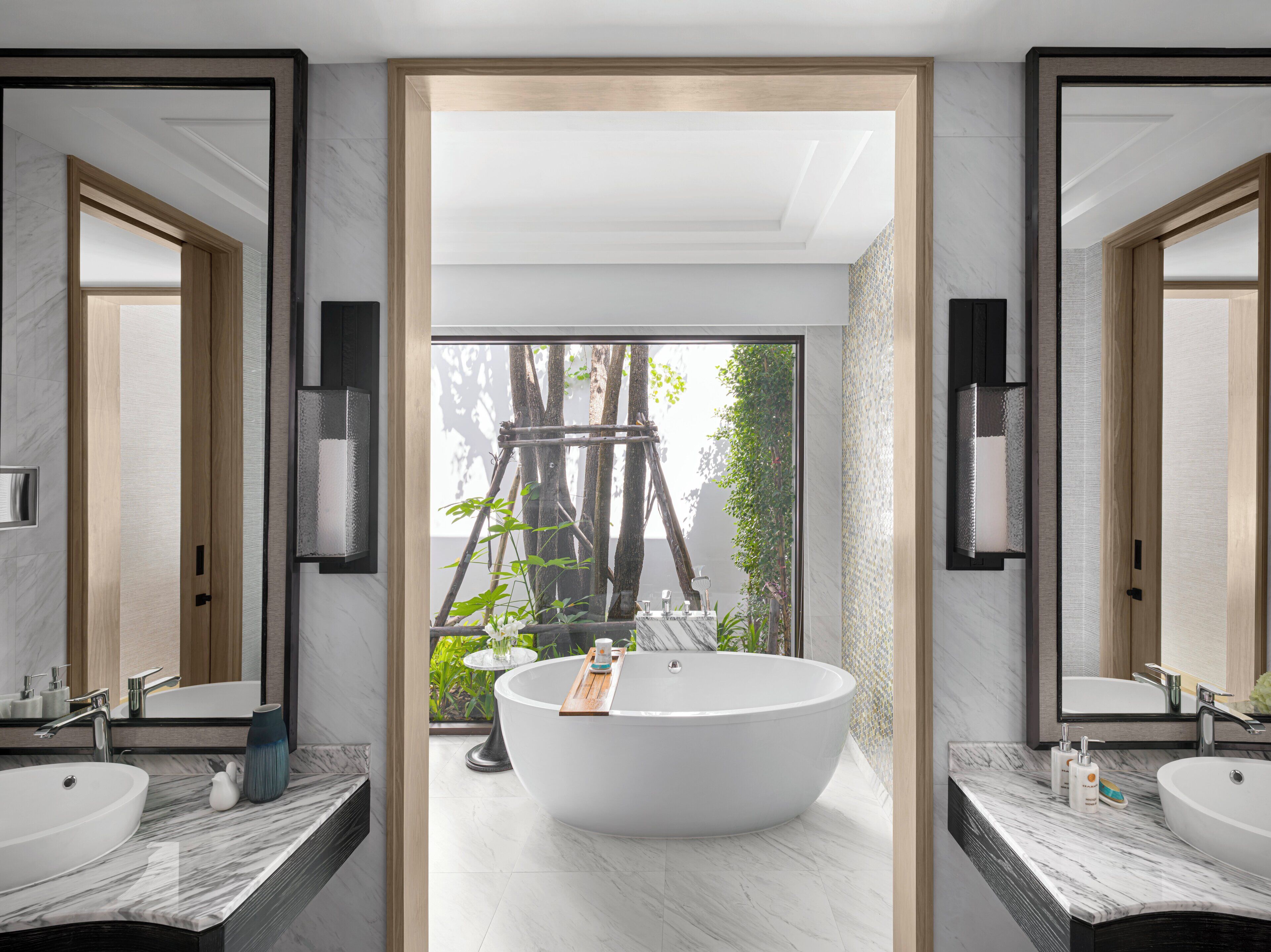 A modern bathroom with a freestanding bathtub, two sinks, and a large mirror.