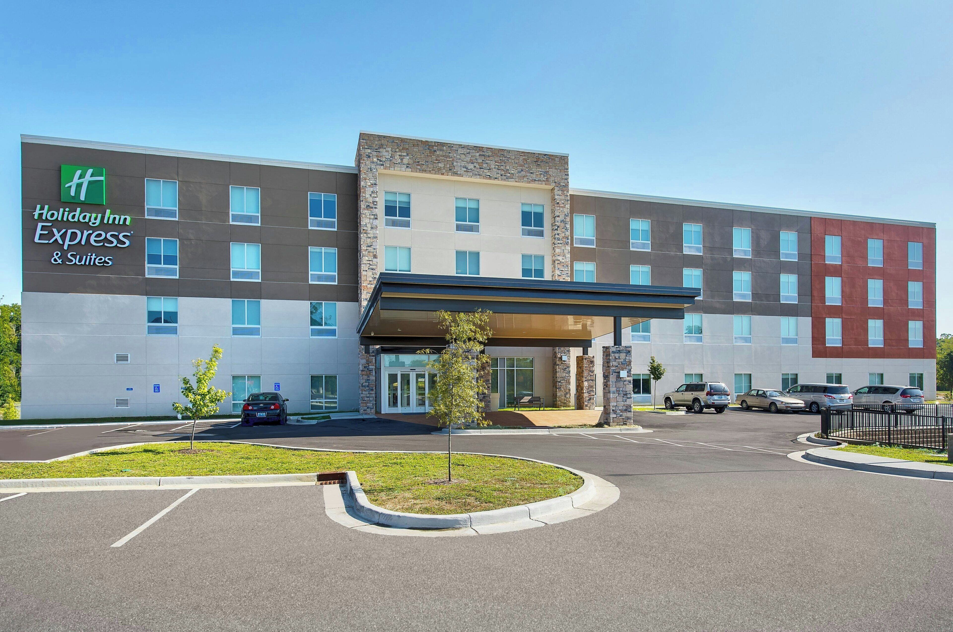 A Holiday Inn Express building with a modern design, a covered entrance, and a parking lot with several cars.