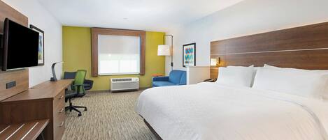 A hotel room with a bed, desk, chair, TV, lamp, and artwork.
