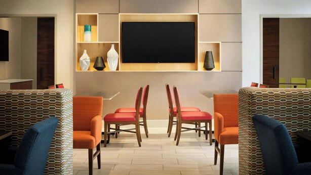 A modern interior with a flat-screen TV, wooden shelves, and patterned seating. - Holiday Inn Express & Suites La Grange by IHG (La Grange)