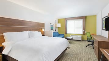 Habitación de hotel con una cama grande, un escritorio, una silla, una lámpara y una ventana.