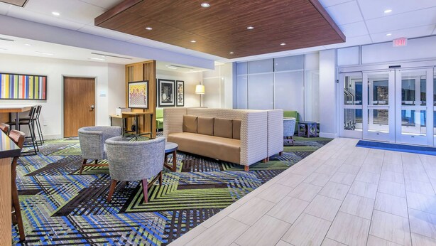 A lobby with a wooden ceiling, a beige sofa, two armchairs, a patterned rug, and a reception desk. - Holiday Inn Express & Suites La Grange by IHG (La Grange)