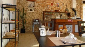 Ein rustikaler Essbereich mit Steinwand, Holzmöbeln und einer Kaffeestation.