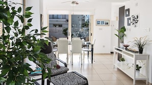 Un salon moderne avec un coin repas, de grandes fenêtres et une vue sur l’extérieur.
