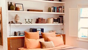A bedroom with a bed, a wooden chair, a bookshelf, and a patterned rug.