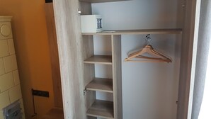 En garderob i trä med flera hyllplan och ett avhängningsutrymme.