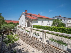 A stone pathway leading to a white building with a red roof and arched windows.
