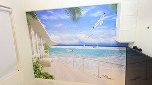Een kamer met een strandmuur, een wit bed en een witte kledingkast.