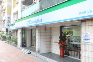 A FamilyMart store with a green and white sign, a tiled entrance, and a potted plant outside. - HF Keelung (Keelung)