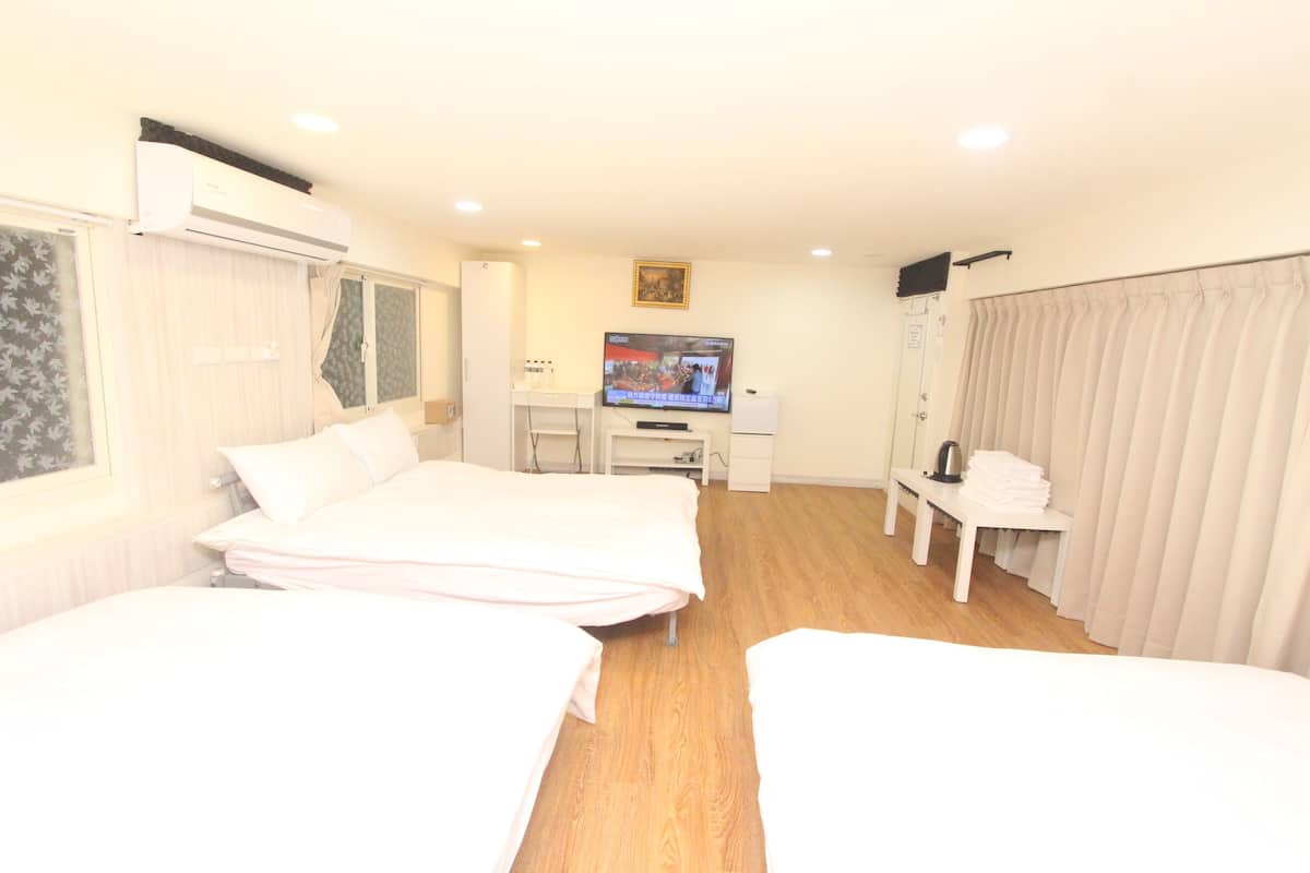 A hotel room with two beds, a desk with a television, and a window with curtains.