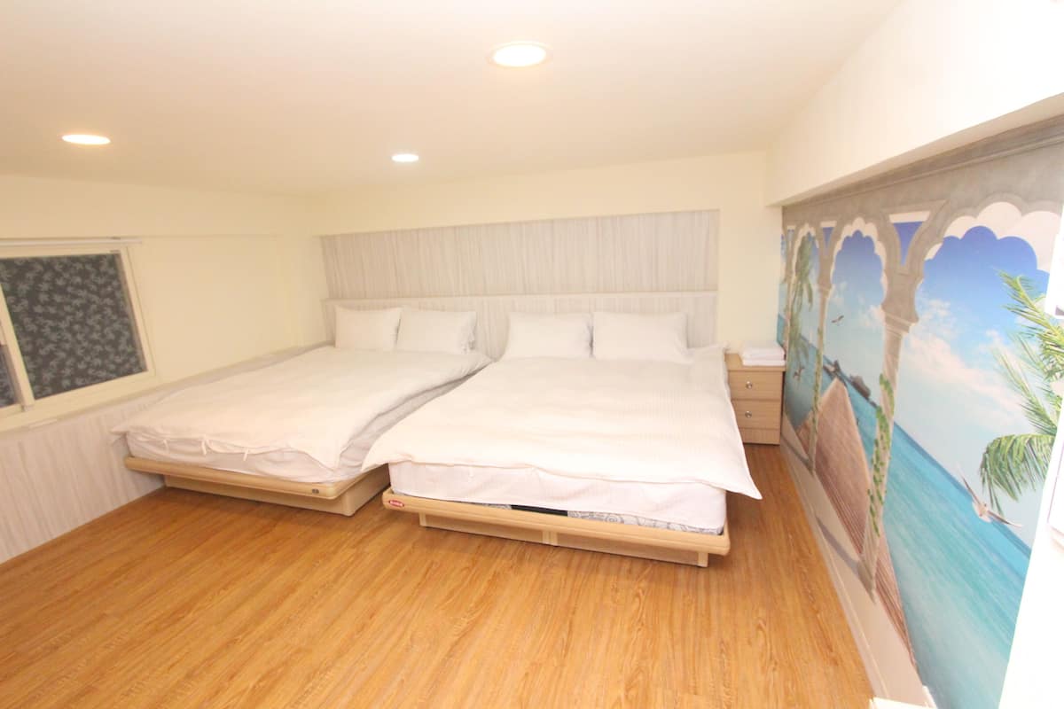 A double bed with a wooden frame and white bedding in a room with wooden flooring and a mural on the wall.
