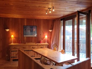 A wooden interior with a dining table, chairs, and a window with curtains. - Chalet-style apt 4/5 pers, center of resort, 50m from slopes (Pra-Loup)