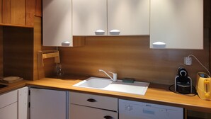 A modern kitchen with a built-in dishwasher, a sink, and a coffee maker.