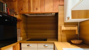 A compact kitchen with wooden cabinets, a built-in oven, and a small sink. - Chalet-style apt 4/5 pers, center of resort, 50m from slopes (Pra-Loup)