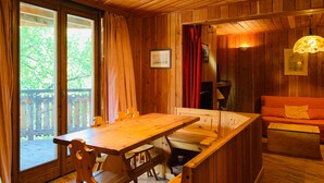 A wooden cabin interior with a dining table, benches, a sofa, and a view of the outdoors. - Chalet-style apt 4/5 pers, center of resort, 50m from slopes (Pra-Loup)