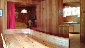 A wooden cabin interior with a dining area, a kitchen, and a cozy living space. - Chalet-style apt 4/5 pers, center of resort, 50m from slopes (Pra-Loup)