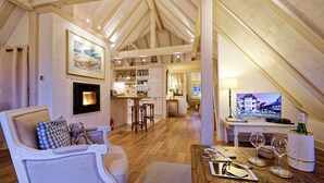 A cozy loft with a fireplace, a dining area, a kitchen, and a TV displaying a scenic view. - The WHITE STORK***** - loft & panoramic views (Riquewihr)