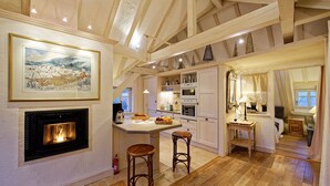 A cozy kitchen with a fireplace, wooden beams, and a dining area with stools. - The WHITE STORK***** - loft & panoramic views (Riquewihr)