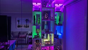 Quarto com um modelo grande e iluminado de uma cidade costeira, incluindo faróis e edifícios, expostos em prateleiras.