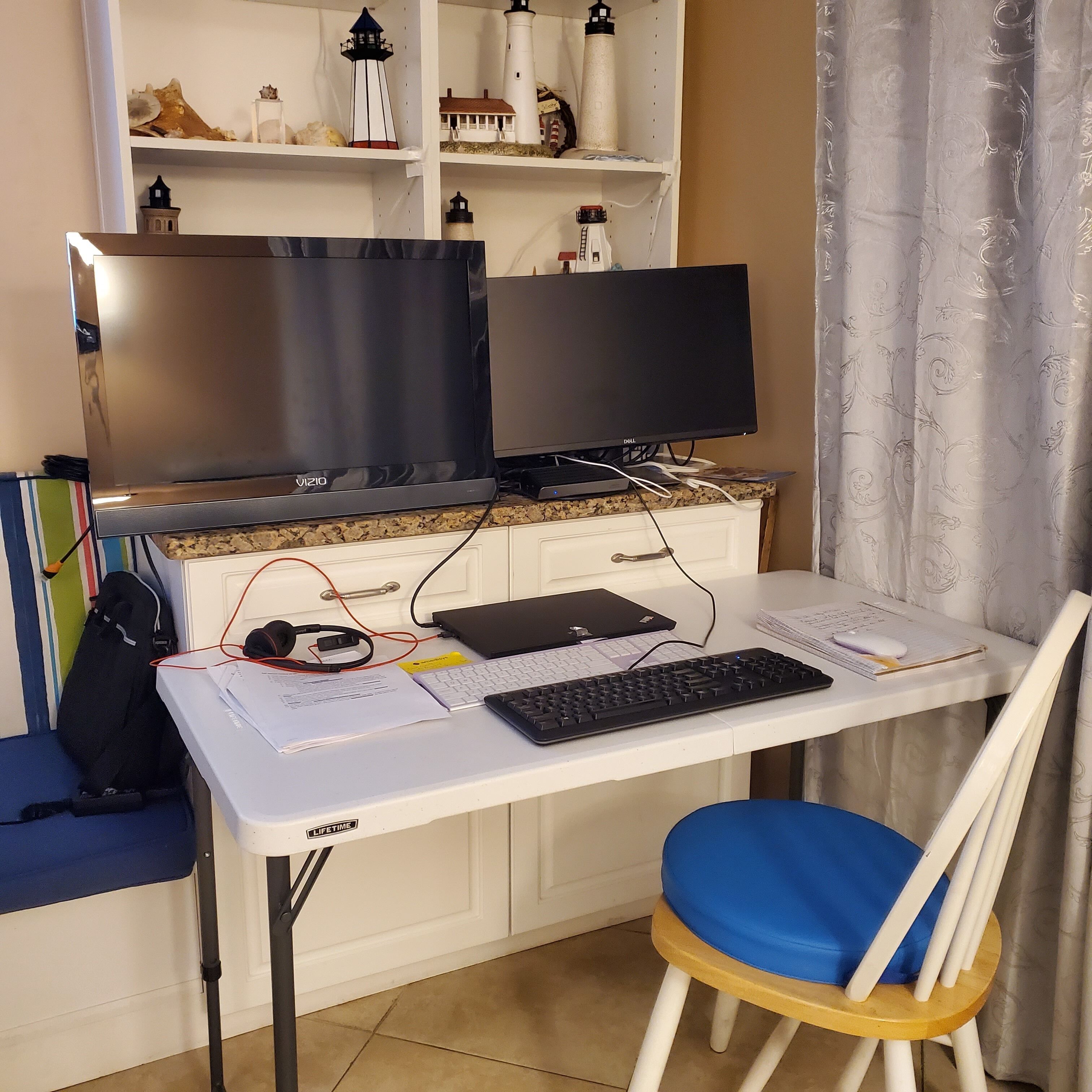 Ein Home-Office-Arbeitsplatz mit Schreibtisch, Computer, Tastatur und Stuhl.