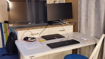Ein Home-Office-Arbeitsplatz mit Schreibtisch, Computer, Tastatur und Stuhl.