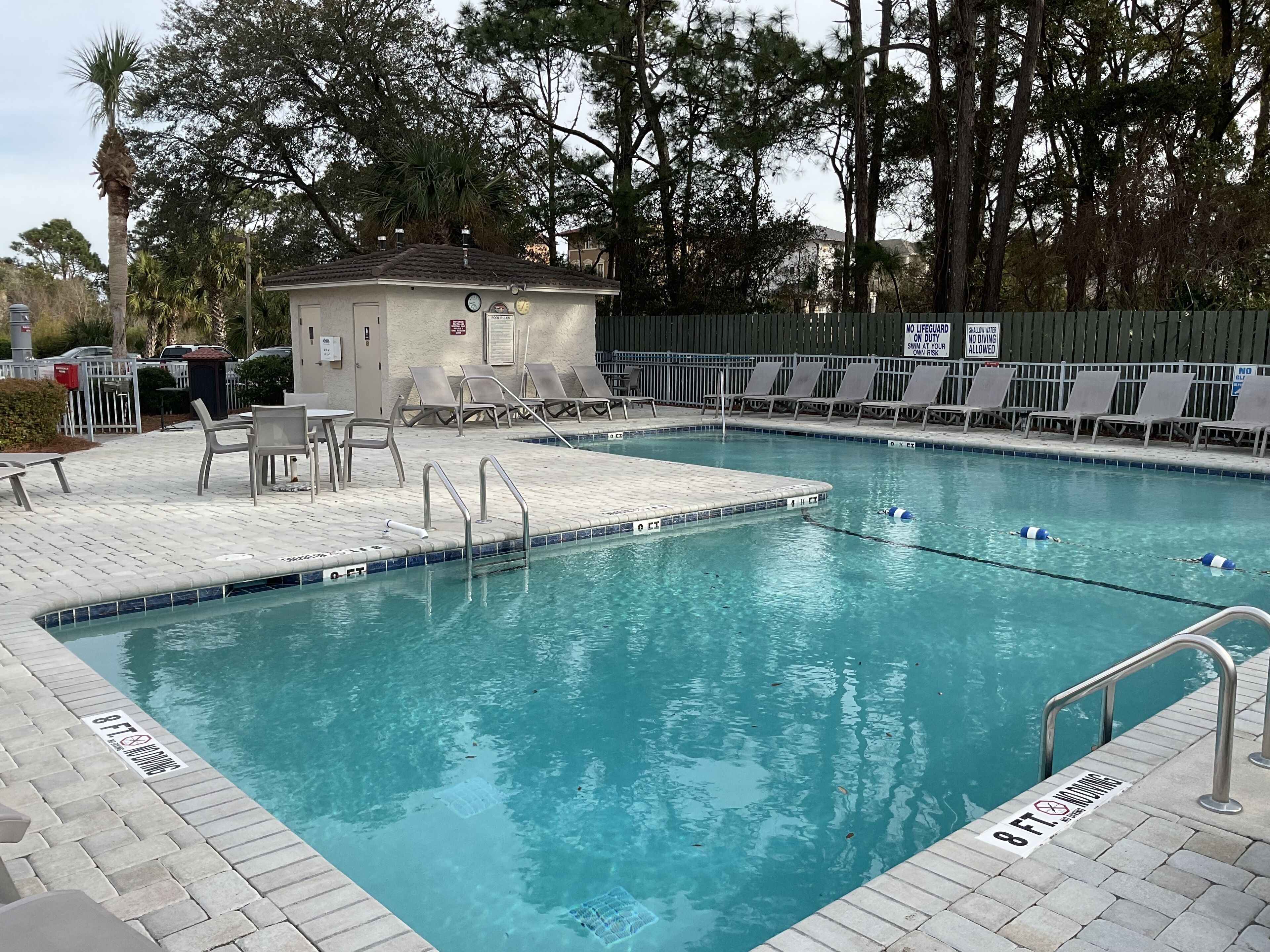 A swimming pool with a lifeguard station, lounge chairs, and a small building.