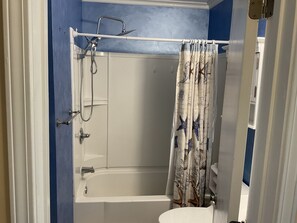 Een bad/douchecombinatie, een haardroger, handdoeken, zeep
