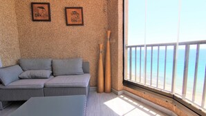 A room with a grey sofa, a small table, and two wooden batons against a textured wall. - ACARI0406-1ºlínea Playa-Wifi y Garaje Gratis. (Calpe)